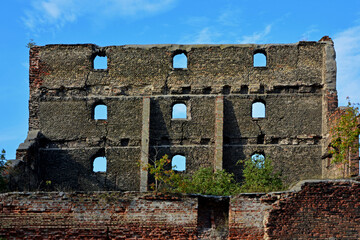 Obraz premium ściana zrujnowanego domu z otworami okiennymi na tle nieba, ruiny domu na tle nieba, the wall of a ruined house with window openings against the sky