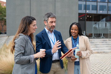 Diverse business team discussing project using digital tablet outdoors