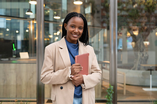 Smiling african american businesswoman holding tablet outside office