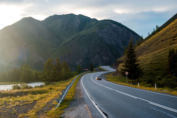 a car is driving along the Chui Highway in the Altai Mountains during sunset