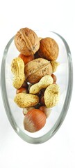 Assorted walnuts, peanuts and hazelnuts placed in a transparent glass bowl on a white background. Natural rustic snack mix for healthy lifestyle, vegan food, recipes, Christmas and autumn themes.