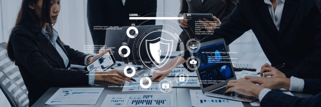 A professional business meeting showcasing modern technology and cybersecurity elements. Participants engage with laptops and tablets, emphasizing teamwork and data protection. Trope - Powered by Adobe