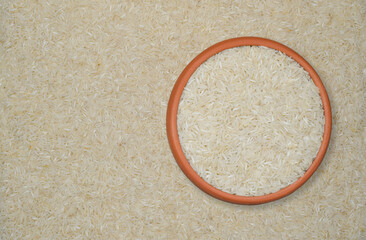 White Rice Grains in a Terracotta Bowl with Scattered Rice