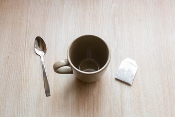 Empty cup with tea bag and spoon on wooden table after a refreshing drink