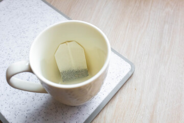 Steaming cup of tea with a teabag steeping in hot water on a simple countertop during a calm morning
