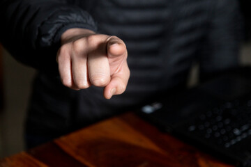 Obraz premium lose up of a man's hand working on a laptop screen and holding a mobile, wearing a black puffer jacket and gold ring. Concept of authority, accusation, or instruction in a business setting.