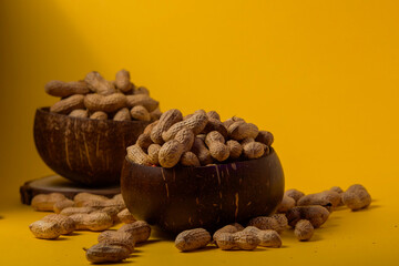 Cacahuetes en cuenco de madera sobre fondo amarillo para fotografía de producto, diseño o publicidad