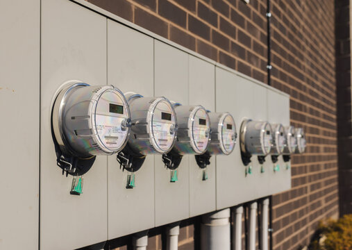 Row of smart electric meters on building exterior for multi-unit energy monitoring