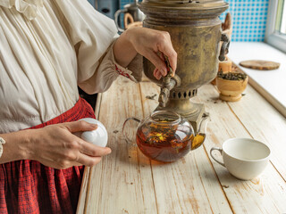Woman is pouring tea into a cup from a teapot