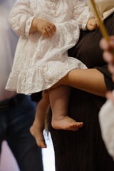 Baby wearing white dress held lovingly in arms during a family gathering at home