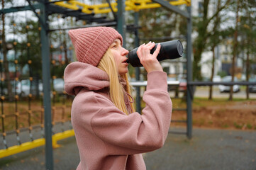 Young woman drinking water after outdoor workout