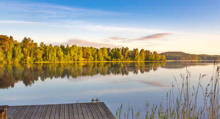 Dock is next to a lake with trees in the background