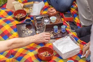 Group of people are sitting on a checkered blanket, enjoying a picnic