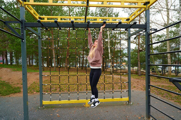 Woman training on outdoor monkey bars at a park