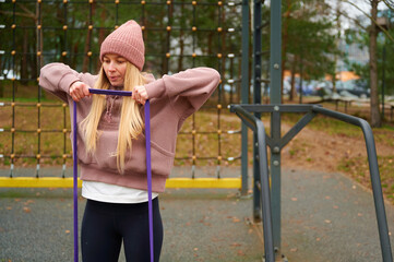 Obraz premium Woman exercising outdoors with resistance band in sports park