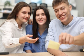 Colleagues discussing strategy near glass board sticky note in office