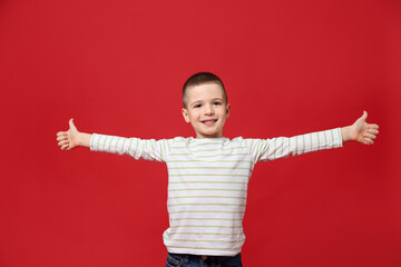 Cute little boy showing thumbs up on red background