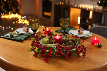 Christmas table setting with plates, glasses and burning candles in festive decorated room, closeup