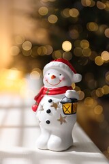 Cute snowman figure on white table against blurred lights indoors, closeup. Merry Christmas and Happy New Year
