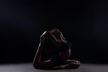 Dramatic silhouette of a woman performing an yoga . Artistic black and white studio fitness...
