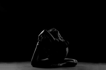 Dramatic silhouette of a woman performing an yoga . Artistic black and white studio fitness photography with rim lighting.