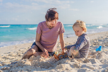 Elderly woman playing on the beach with her young grandson, enjoying a joyful family moment by the sea. Concept of active aging, family bonding, summer fun, and multigenerational connection