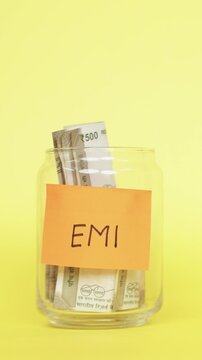 Vertical Video of Saving money for EMI. Putting Indian Rupee notes in Glass Jar