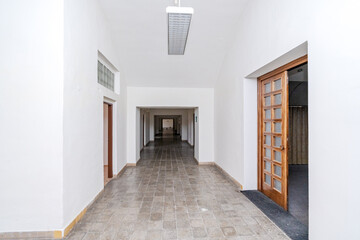 Empty long hallway perspective with tiled floor and multiple doors