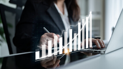 A business professional engages with data trends using a laptop, featuring a digital graph overlay, representing growth and strategic success in a modern office space. Impute