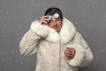 A man in a luxurious white fur coat with a hood and glasses for protection from snow, dynamically...