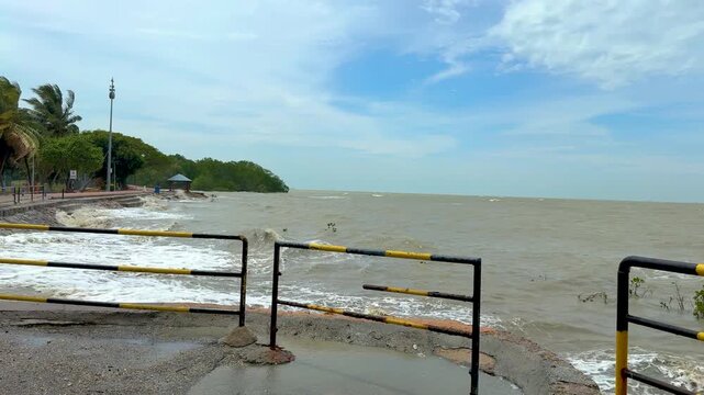 Strong waves hitting the seawall during rough sea conditions near the mangrove area.