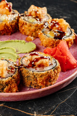 Close-up of tempo sushi rolls with fresh fish, rice, and garnishes.
