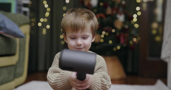 A little boy blow-dries his hair at home, slow motion
