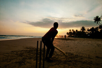 silhouette of kid playing cricket on sunset beach Sri Lanka