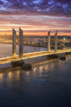 Aerial view of the Jacques Chaban-Delmas bridge reflected in the Garonne river under a fiery sunset sky, Bordeaux, Nouvelle-Aquitaine, France.