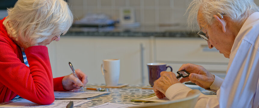Senior elderly couple keeping mind active by doing crossword puzzle - Powered by Adobe