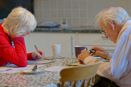 Senior elderly couple keeping mind active by doing crossword puzzle