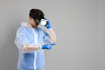 Modern technology. Doctor in headset using virtual screen on grey background. Space for text