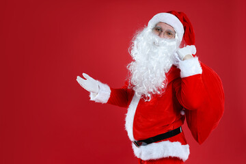 Santa Claus with bag of gifts on red background, space for text. Merry Christmas and Happy New Year