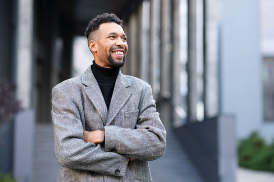 Smiling man in suit with crossed arms on city street. Space for text - Powered by Adobe