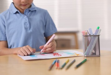 Cute little boy drawing family at wooden table indoors, closeup