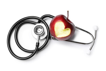 Ripe apple with carved heart and stethoscope isolated on white, top view