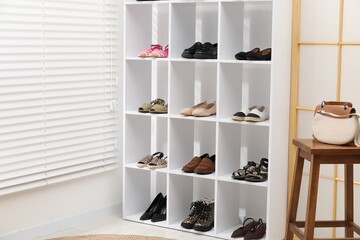 Different pairs of shoes on shelves near white wall indoors