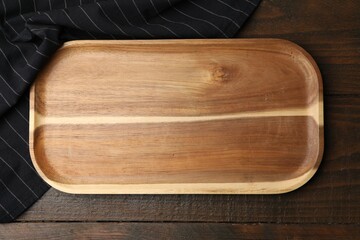 One serving board and napkin on wooden table, top view. Space for text