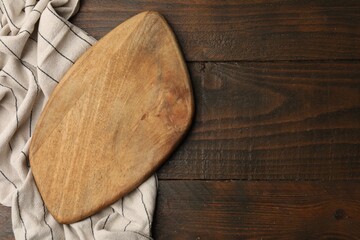 One cutting board and napkin on wooden table, top view. Space for text