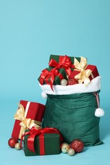 Santa Claus bag with Christmas gifts and balls on light blue background