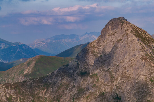 Aerial view of rugged Tri Kopy peak, its rocky face contrasting with the softer, distant Zilinsky kraj mountains under a sky streaked with pastel hues, Ziar, Zilinsky kraj, Slovakia.