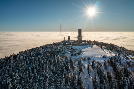 Aerial view of the snowy peak of Grosser Feldberg piercing a sea of clouds under a bright sun, Schmitten im Taunus, Hessen, Germany.