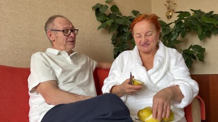 wife cuts off piece of pear and treats husband Face, love and smile with senior couple in home together for bonding, safety or relationship. Marriage, relax and security with happy elderly people
