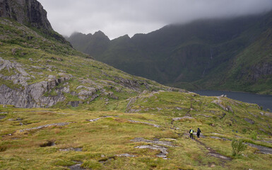 Hikers trekking in a nature trail. Lofoten Islands, A village Norway